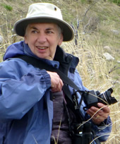 Kathy wears a blue jacket and hat as she holds her camera.